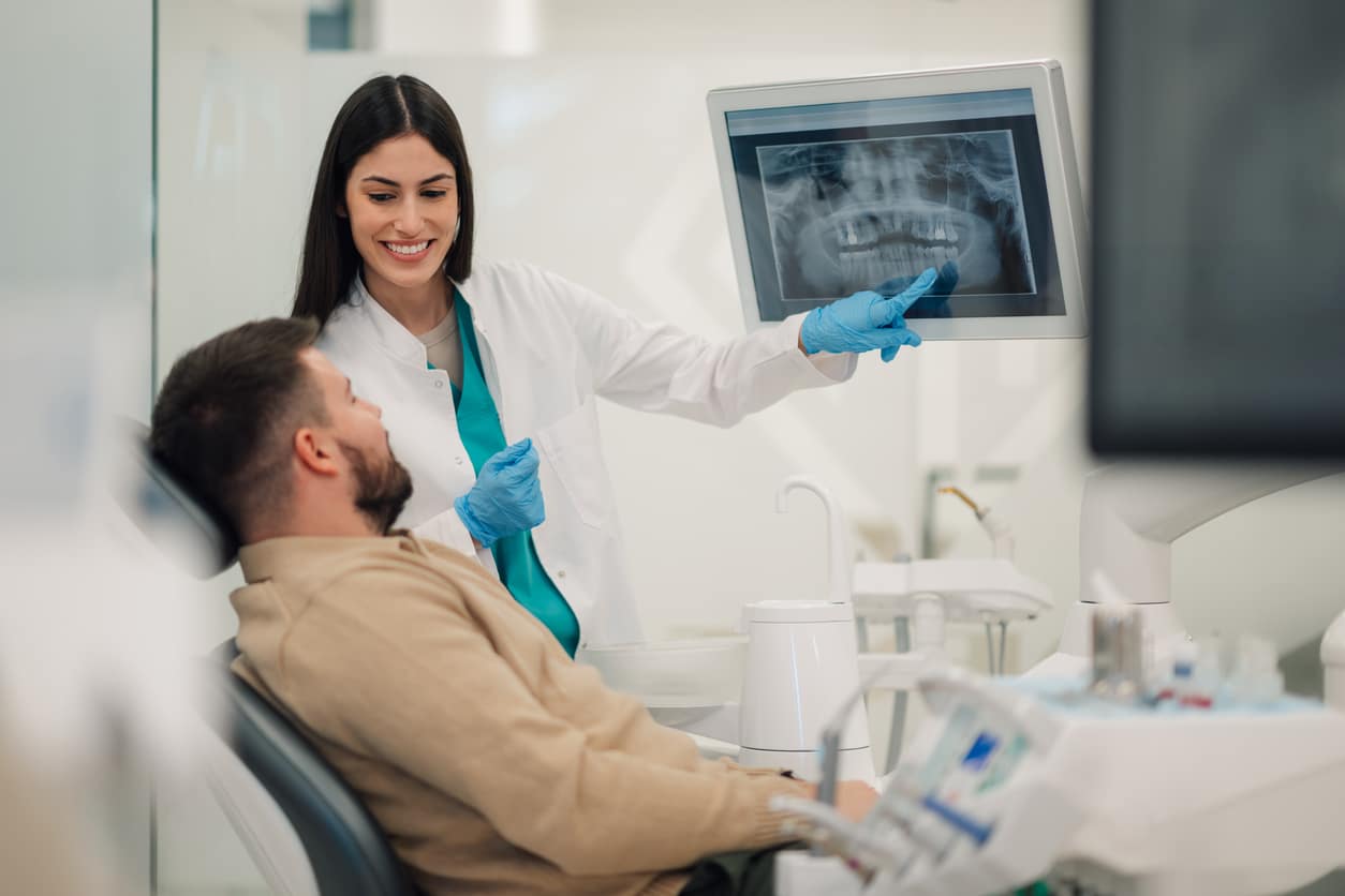 Dentist showing teeth x-ray to patient in modern clinic HIPAA for Dental Offices